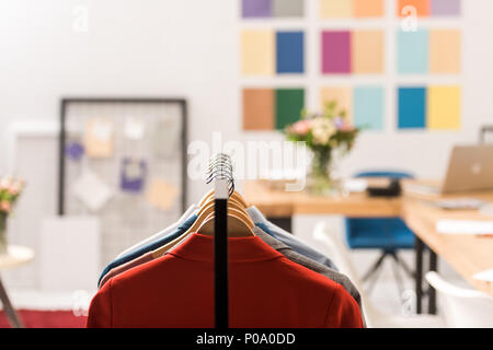 selective focus of fashionable clothes on hangers in modern office Stock Photo