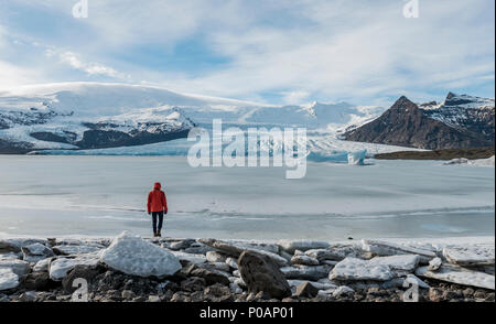 Man stands at Frozen Lagoon with ice floe, mountains, Fjallsárlón Glacier Lagoon, South Iceland, Iceland Stock Photo