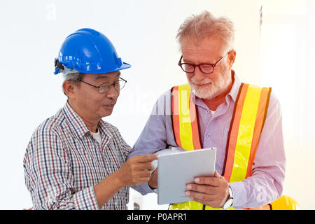 two engineer mix race looking at tablet screen using technology with CAD for construction and design concept. Stock Photo
