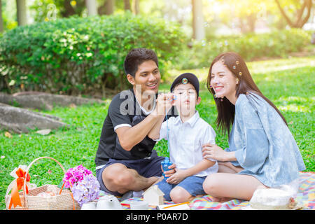 dad mom and son enjoy picnic family day holiday at green park Stock Photo