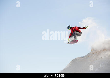 Image of man in helmet with snowboard jumping from snowy mountain slope Stock Photo