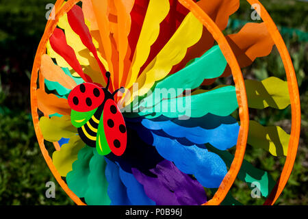 windmill spinning in wind on green nature background.decoration element in garden. Kids colorful windwill. bright nature background. Stock Photo