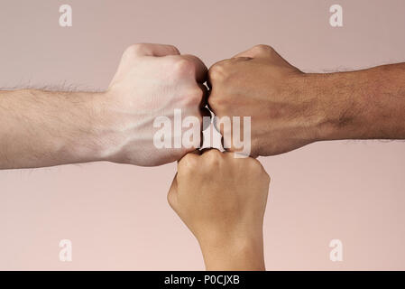 Hands fists together of different color skin people isolated on brown background Stock Photo