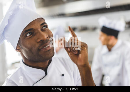 handsome african american chef pointing up at restaurant kitchen Stock Photo