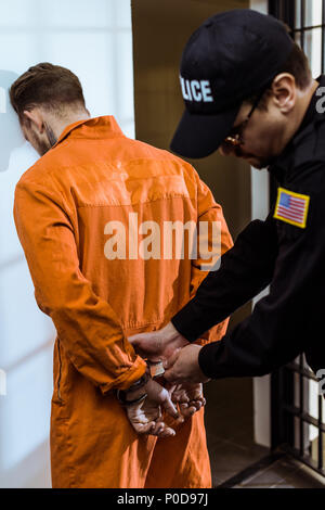 prison guard wearing handcuffs on prisoner Stock Photo