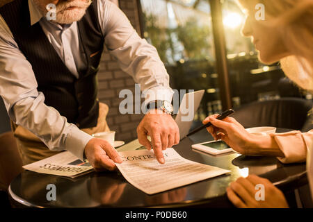 partial view of business partner signing contract at business meeting in cafe Stock Photo