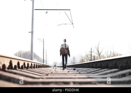 Teenager on railway walking with small white dog Stock Photo