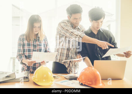 Young male and female architect colleagues drawing graphic planning of interior creation project cooperating with talented teacher giving advice and c Stock Photo