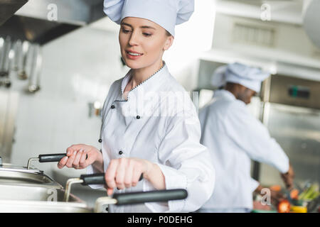 attractive chef frying food in oil at restaurant kitchen Stock Photo