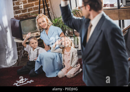 selective focus of father going to work and waving hand to happy family, 1950s style Stock Photo