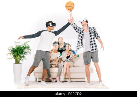 young multiethnic friends in virtual reality headsets playing with basketball ball isolated on white Stock Photo
