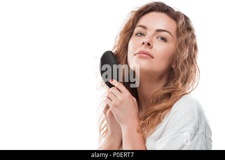 Beautiful blonde woman in bathrobe combing hair and looking at camera Stock Photo