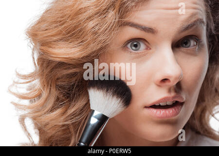 Close-up view of pretty blonde woman applying makeup with brush Stock Photo