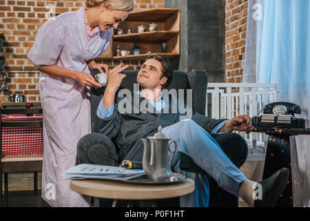 https://l450v.alamy.com/450v/p0f1ht/smiling-man-in-robe-smoking-cigarette-and-looking-at-happy-wife-holding-cup-of-coffee-1950s-style-p0f1ht.jpg