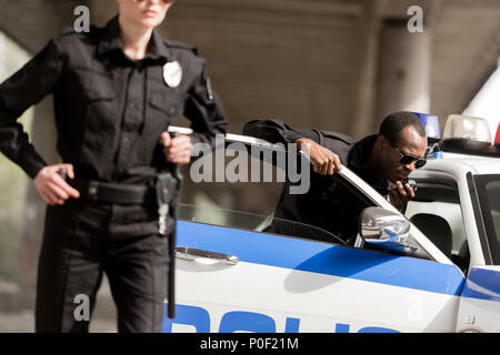 young police officers standing near car Stock Photo