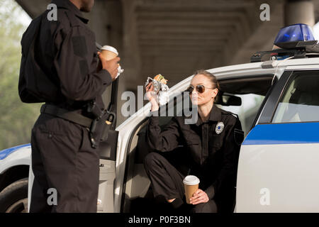 two police officers drinking coffee and eating burger Stock Photo