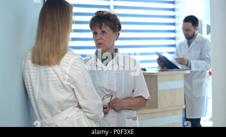 Two nurses talking near reception desk Stock Photo