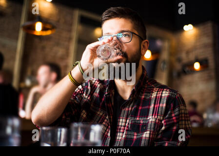 Bearded hipster man drinking water in a coffee bar Stock Photo
