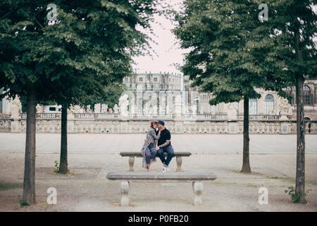 beautiful stylish young couple hugging and kissing on bench in Dresden, Germany Stock Photo