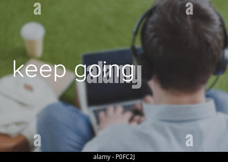 close-up shot of man in headphones using laptop, keep going inscription Stock Photo