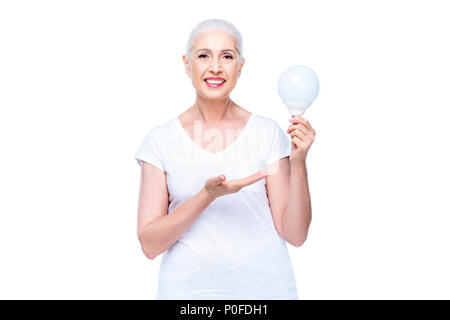 smiling senior woman presenting light bulb, isolated on white Stock Photo
