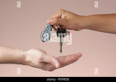 Giving car keys concept. Hand holding auto keys. Sell vehicle service. Hands hanging keys isolated Stock Photo
