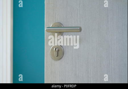 Opened door with metal door knob into blue room Stock Photo