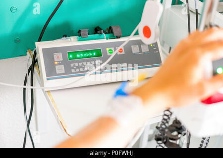 Hand with peripheral venous catheter and equipment to dose epidural during delivery Stock Photo