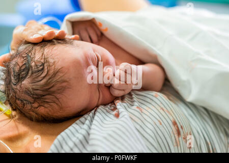 Newborn baby boy laying down on his mom with her carying hand on him Stock Photo