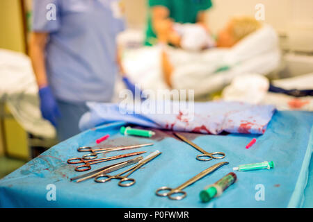 Silver gynecologist tools used during childbirth and mother and hospital staff in the background Stock Photo