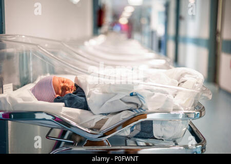 Newborn baby boy in his small transparent portable hospital bed Stock Photo