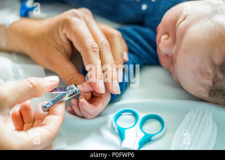 Mother cuts fingernails of her newborn baby boy in the hospital Stock Photo