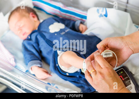 Using oximeter on newborn baby boy to check his level of oxygen in the hospital Stock Photo