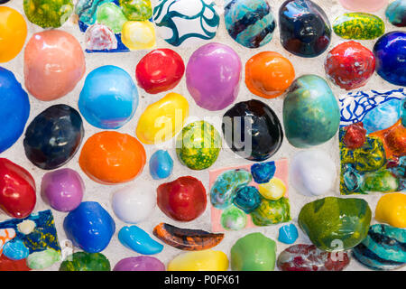 Background formed by a wall made of colored stones and multicolored ceramic pieces. Stock Photo