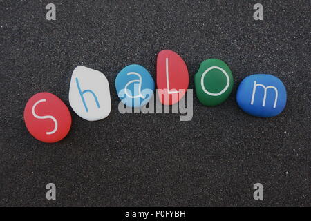 Celebration of the word Shalom with a multi colored sea stone òetters over natural black volcanic sand Stock Photo