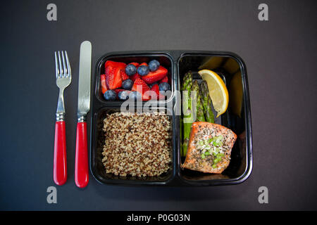 Planned meals in containers - salmon with asparagus, quinoa and fresh fruit. Stock Photo