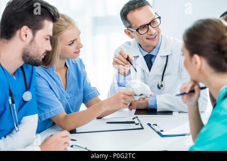 young team of doctors and general practitioner having conversation and holding plastic brain model Stock Photo