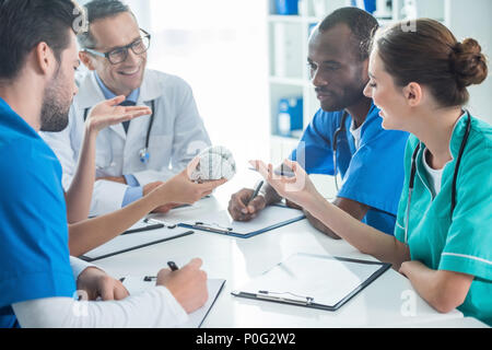 multiethnic team of doctors and general practitioner having conversation and holding plastic brain model Stock Photo