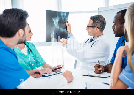 multiethnic team of doctors looking at x-ray scan of pelvis Stock Photo
