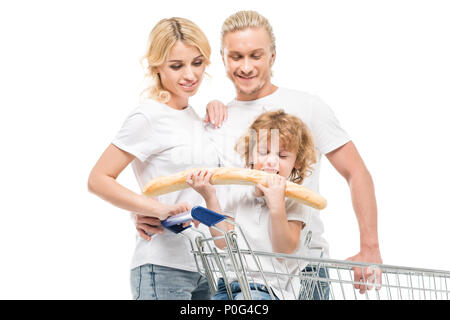 little boy eating bread while sitting in shopping cart with parents near by isolated on white Stock Photo