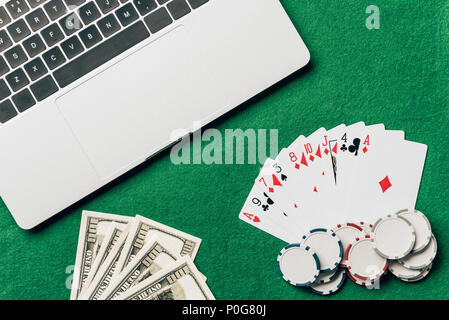 Online gambling concept with cards and money on table by laptop Stock Photo