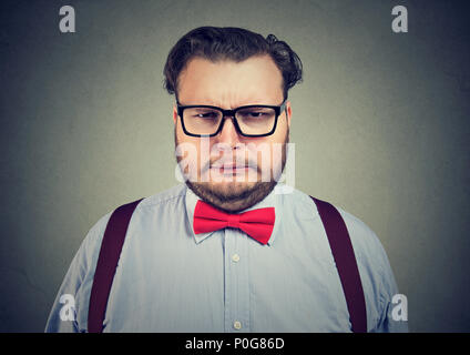 Overweight formal man wearing glasses and making complaining expression of face looking at camera on gray Stock Photo