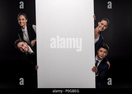 Group of business people holding blank billboard and looking at camera isolated on black Stock Photo