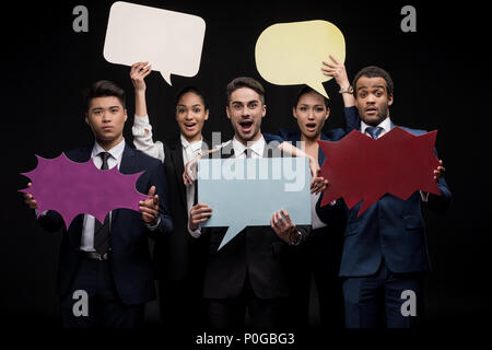 Group of businesspeople holding blank speech bubbles isolated on black Stock Photo
