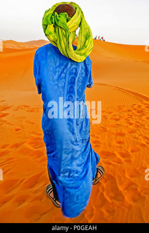 Young camel driver wearing blue dress in Moroccan desert Stock Photo