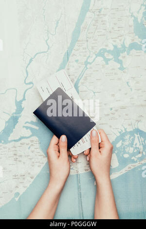 cropped shot of woman holding flight ticket and passport on travel map Stock Photo