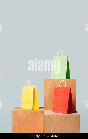 three colored shopping bags on wooden stands isolated on white, summer sale concept Stock Photo