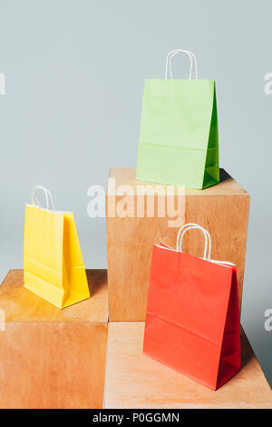 three colored shopping bags on wooden stands, summer sale concept Stock Photo