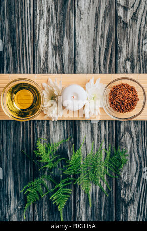 top view of arranged oil, scrab, candle and chrysanthemum flowers for spa and massage on wooden tabletop Stock Photo