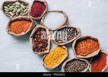 top view of colorful spices in paper bags on white table Stock Photo